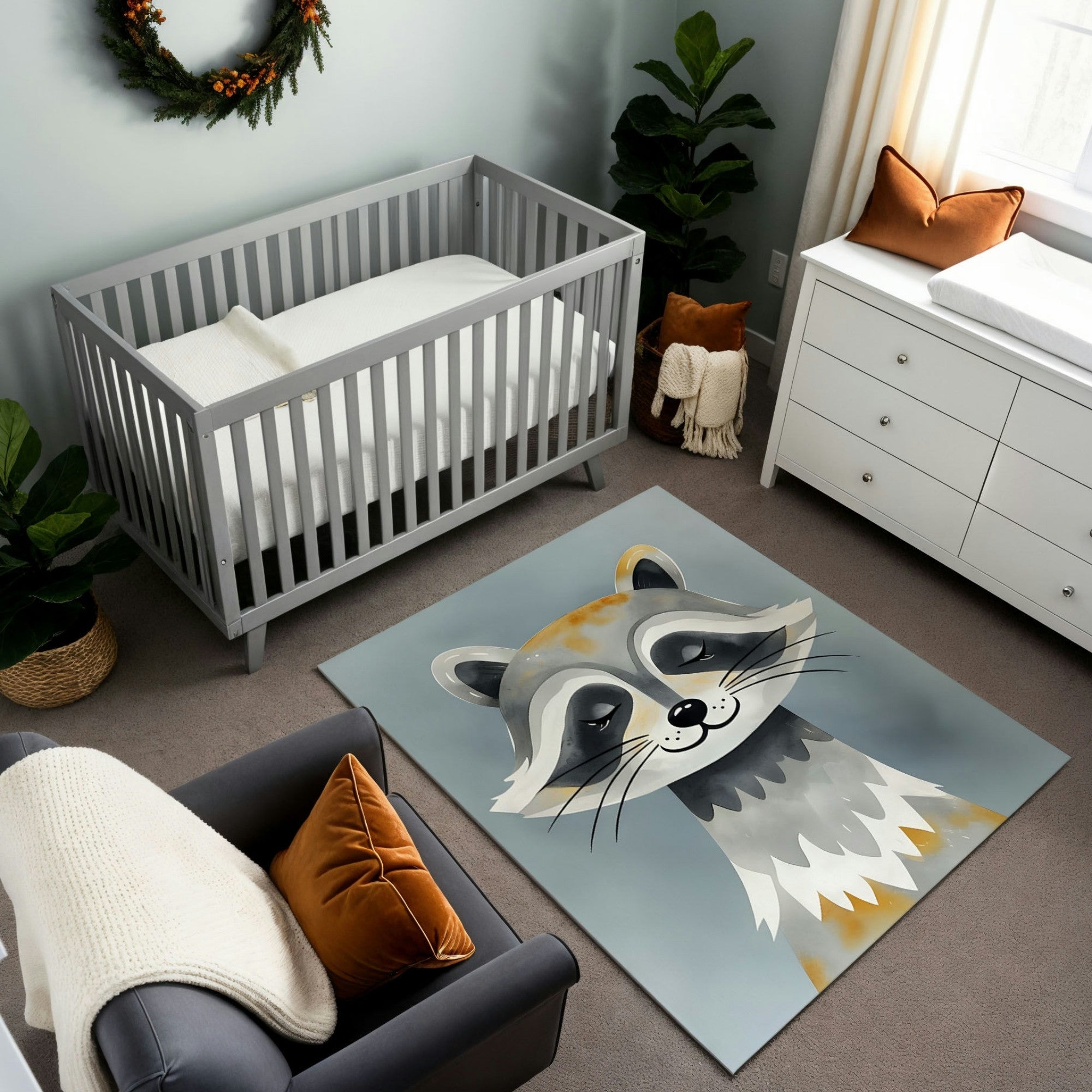 This nursery features a serene and cozy design with soft gray tones and earthy accents. A gray crib pairs beautifully with a white dresser and a plush gray armchair adorned with an orange throw pillow and cream knit blanket. The standout feature is a charming rug depicting a smiling raccoon in gray and beige tones, harmonizing perfectly with the room’s calm and woodland-inspired theme. Natural greenery and a festive wreath complete the inviting atmosphere.