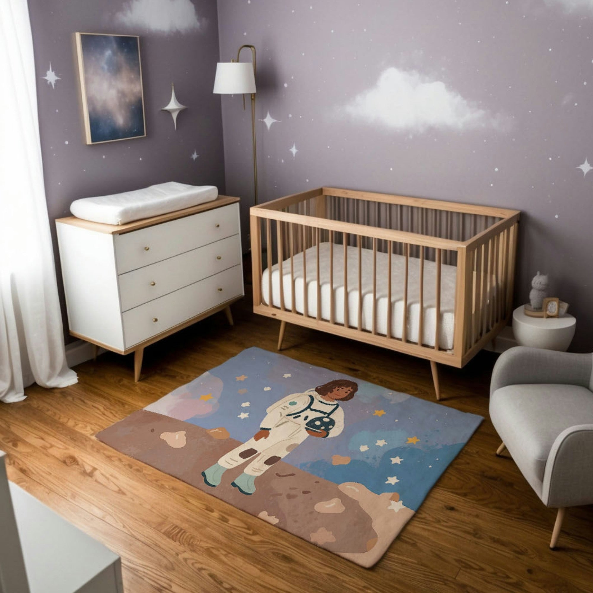 This nursery features a calming space-themed design with soft gray walls adorned with stars and clouds, creating a dreamy celestial ambiance. A natural wood crib and white dresser add warmth, while a cozy gray armchair provides a comfortable seating area. The centerpiece is a colorful rug depicting an astronaut standing on a rocky planetary surface, set against a starry sky, sparking imagination and adventure. The combination of soft lighting, natural tones, and whimsical space elements make this room both 