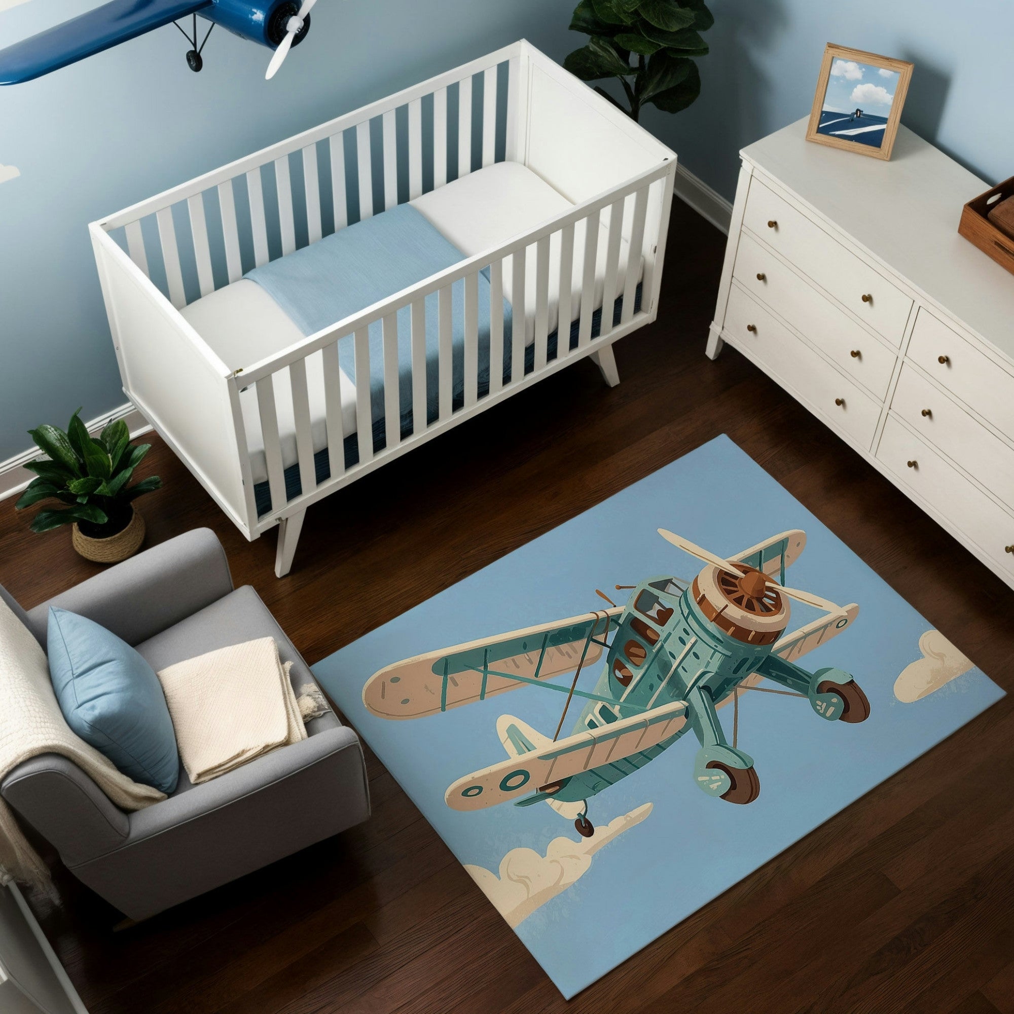 The image shows a cozy nursery with a crib and dresser set against a light blue wall, featuring a vintage aviation theme. The floor is adorned with a decorative rug illustrating a classic biplane in green and beige tones flying through a blue sky with white clouds, complementing the room’s airy, adventurous vibe. The decor includes a model airplane hanging from the ceiling, adding a whimsical touch to the setting.